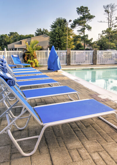 Poolside lounge chairs lined up beside calm water.
