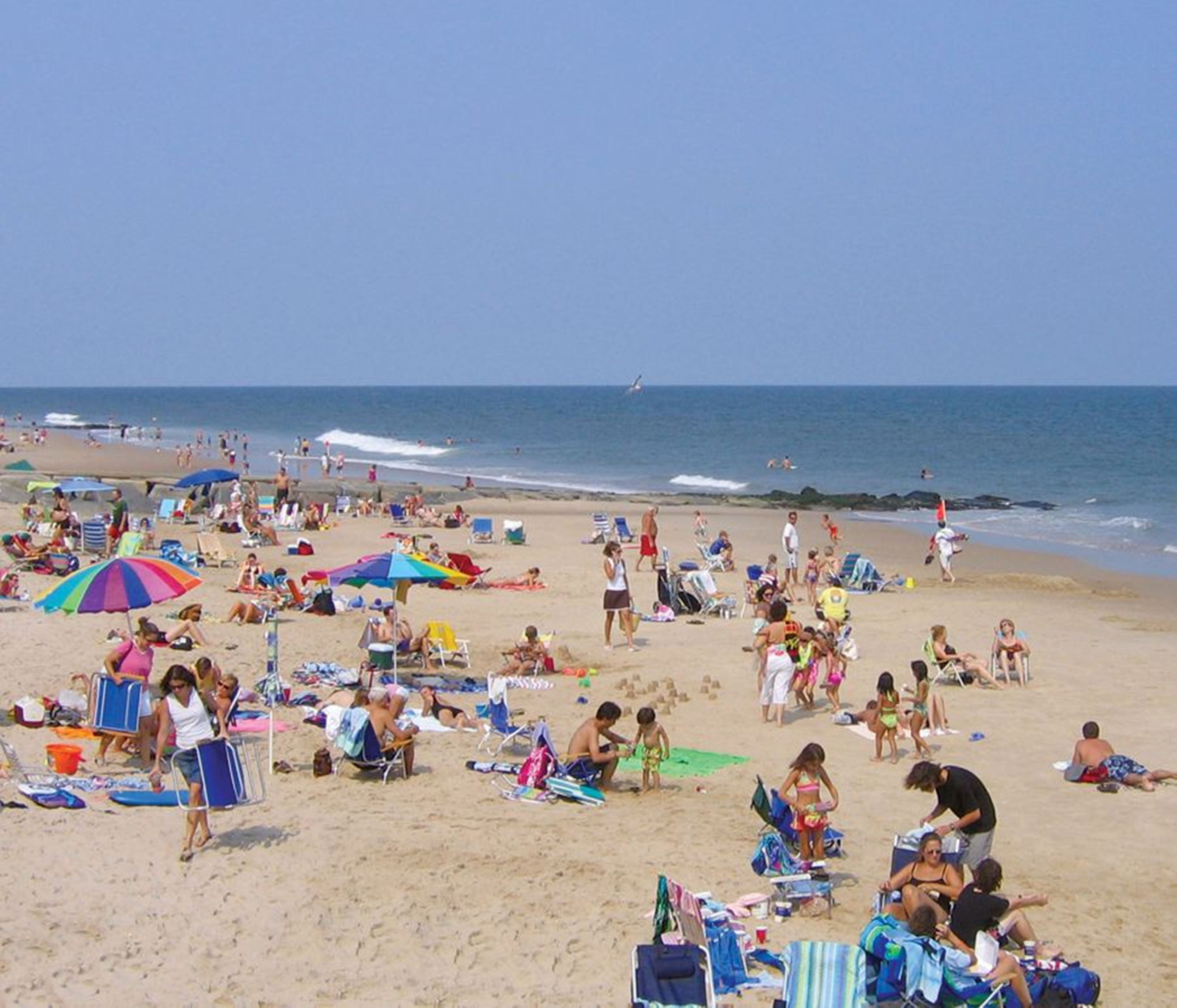 Busy sandy beach with umbrellas and families.