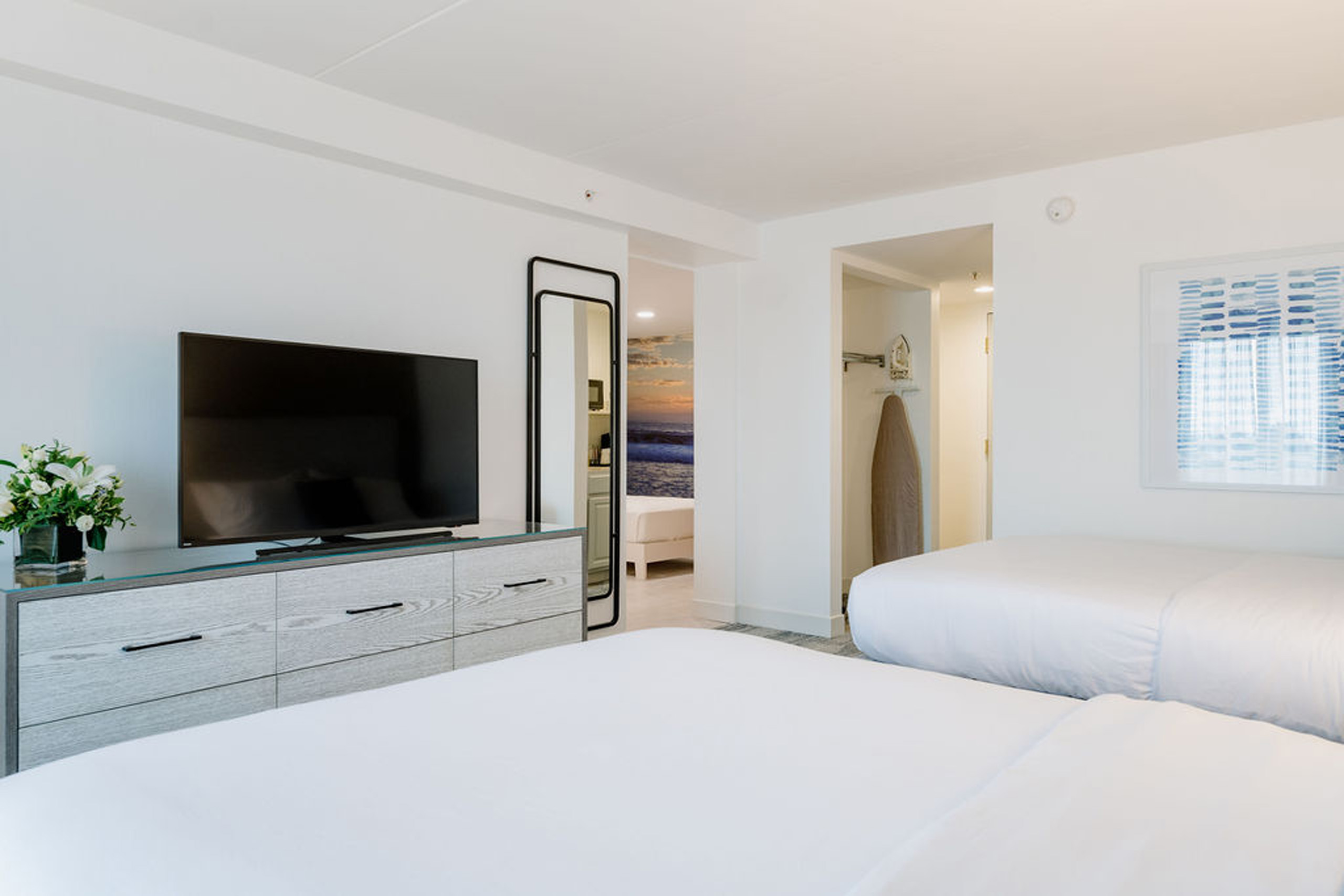 Hotel room with TV, beds, and mirror view.