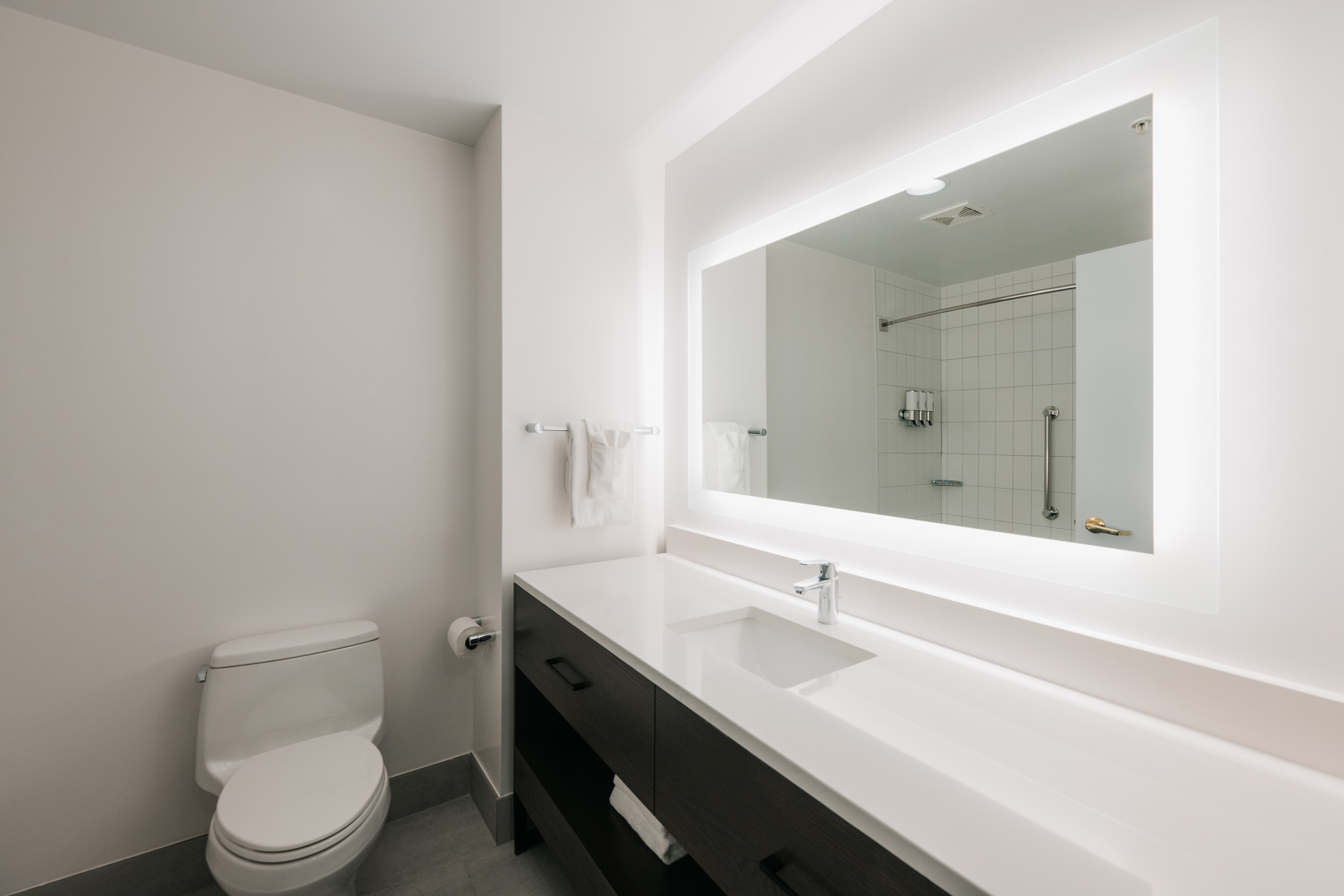 Bright bathroom with large mirror and white vanity.