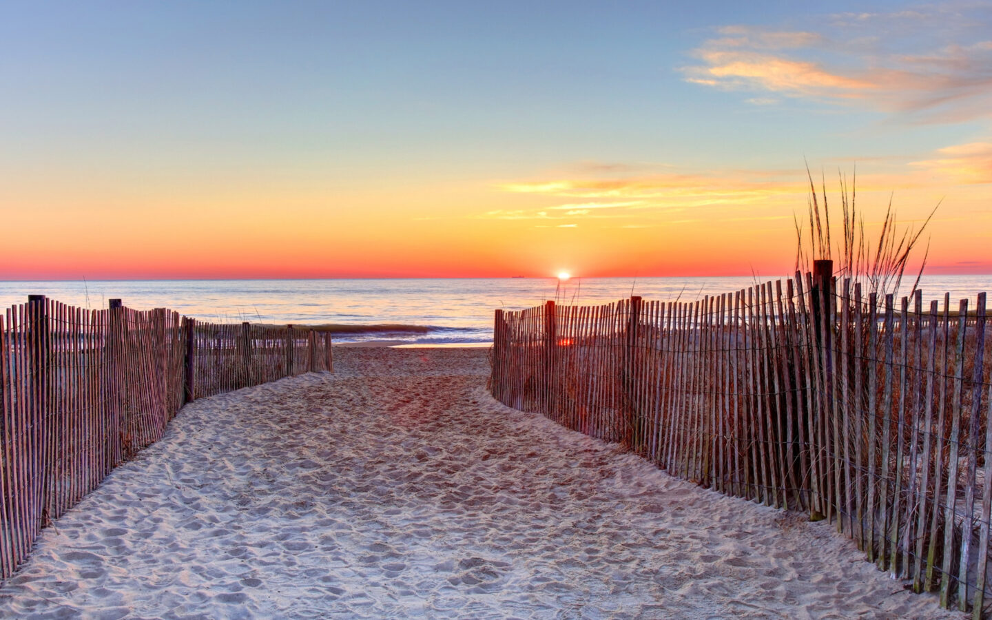 Sandy path leading to beach at sunrise.