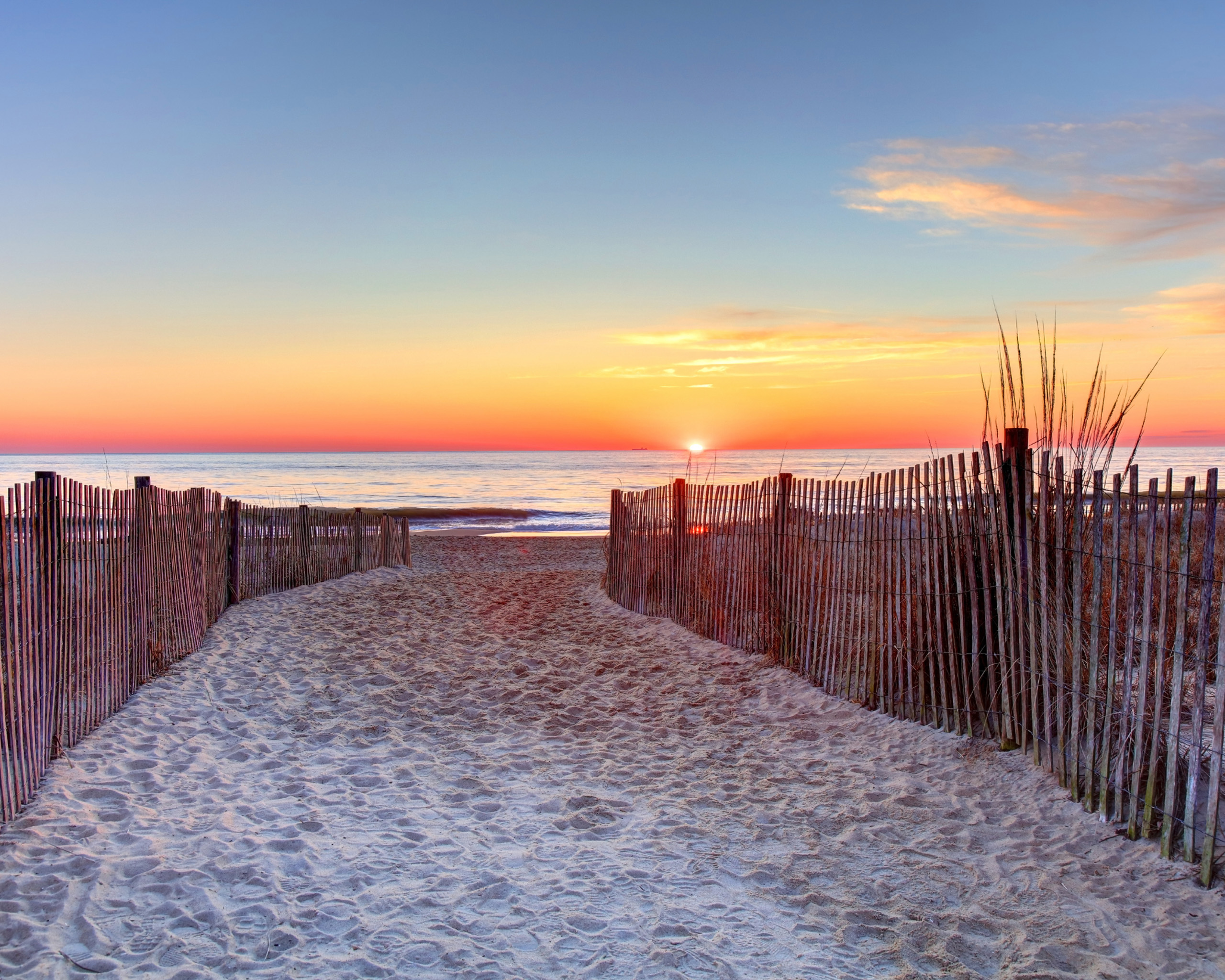 Sandy path leading to beach at sunrise.