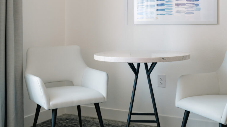 Small round table with two modern white chairs.