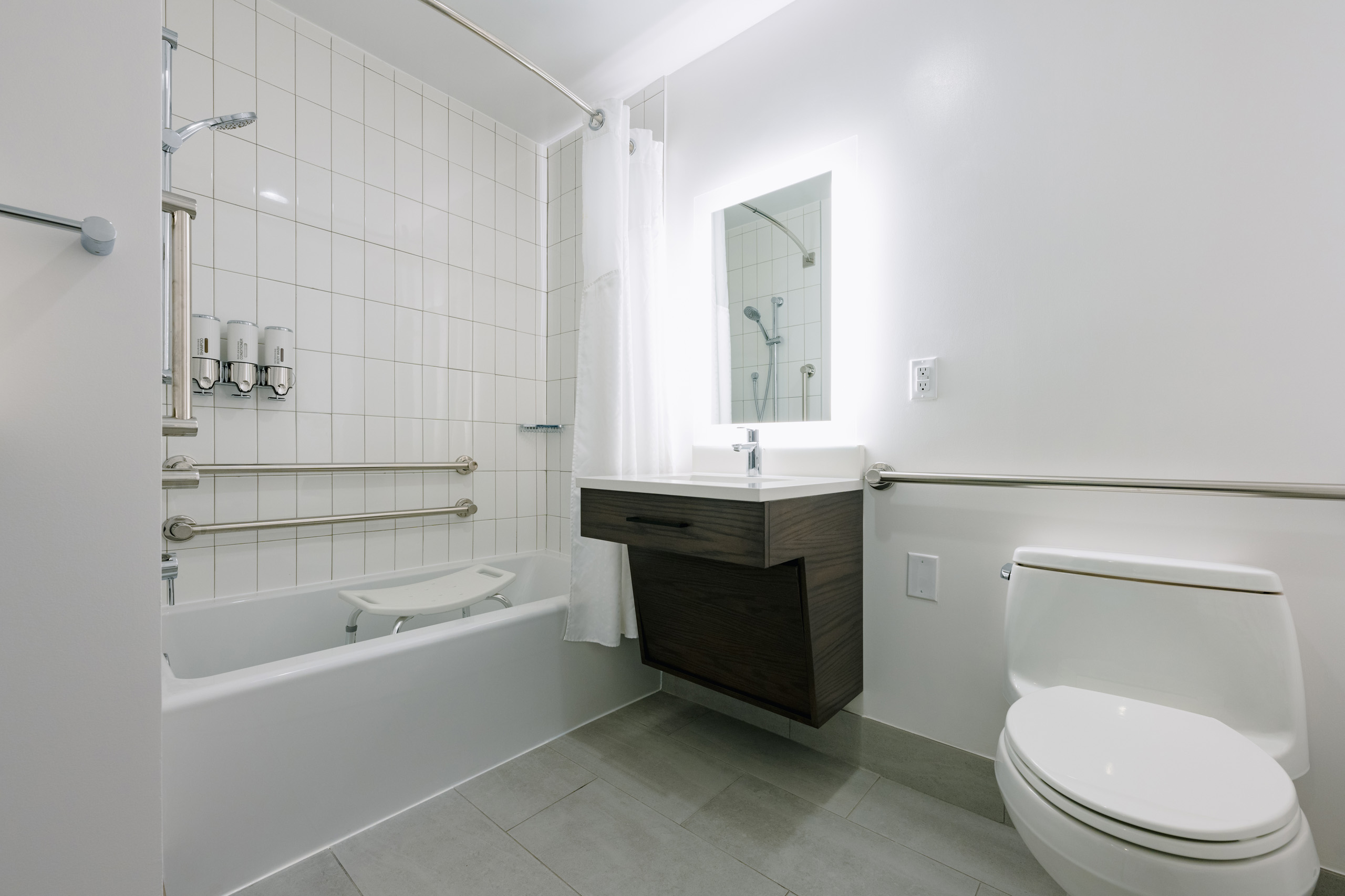 Accessible bathroom with tub, grab bars, and shower seat.