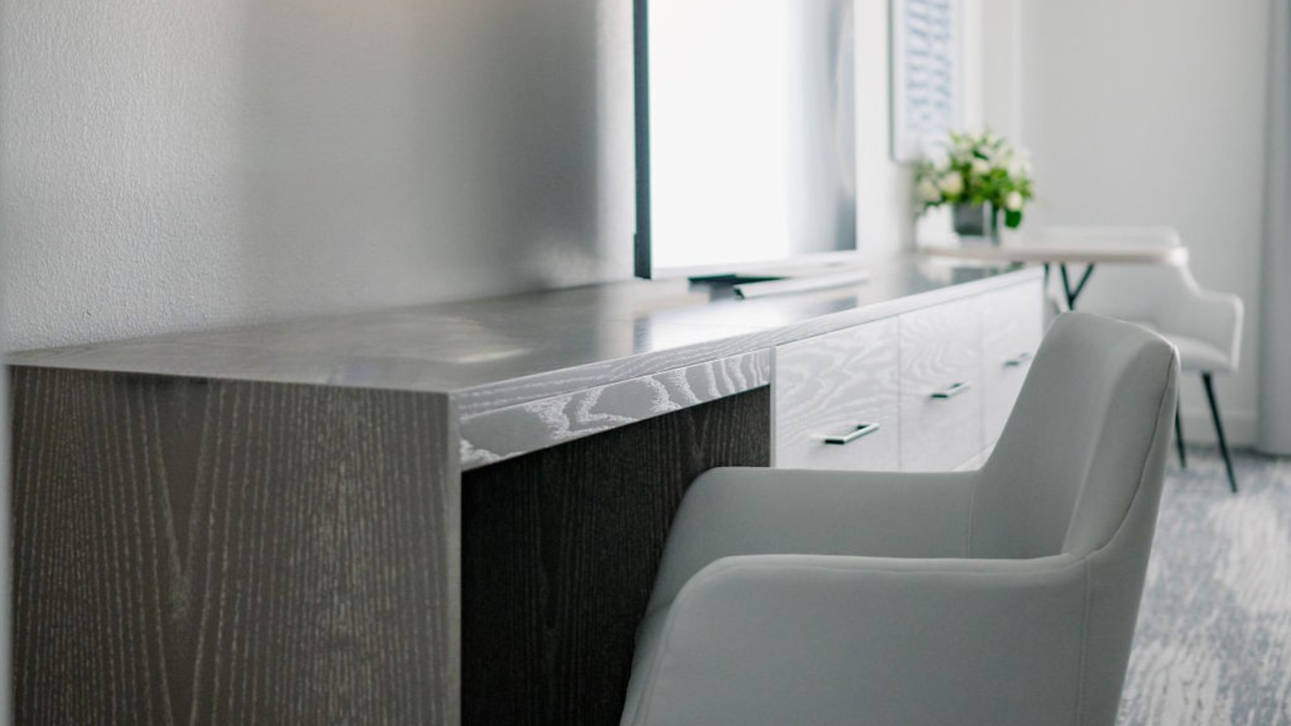 Desk with chair facing TV and bright window.
