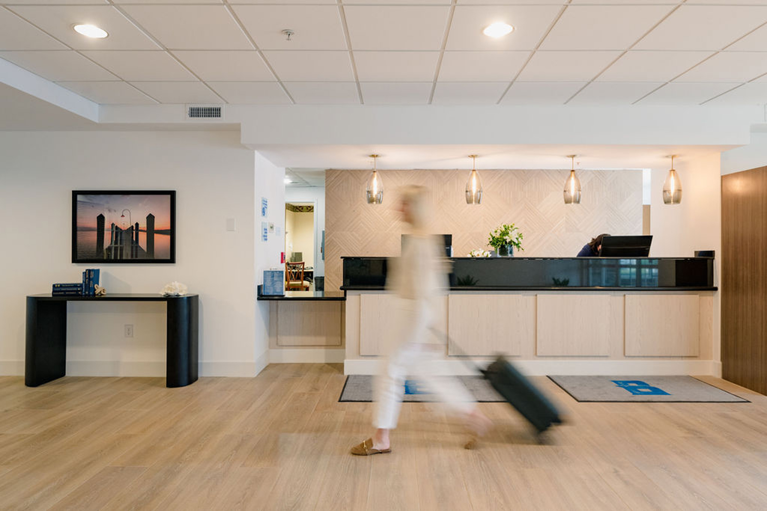 Traveler walking through modern hotel lobby with suitcase.