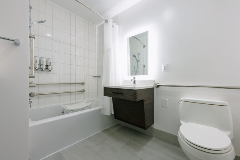 Accessible bathroom with tub, grab bars, and shower seat.