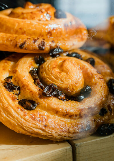 Freshly baked pastries with raisins in bakery display.