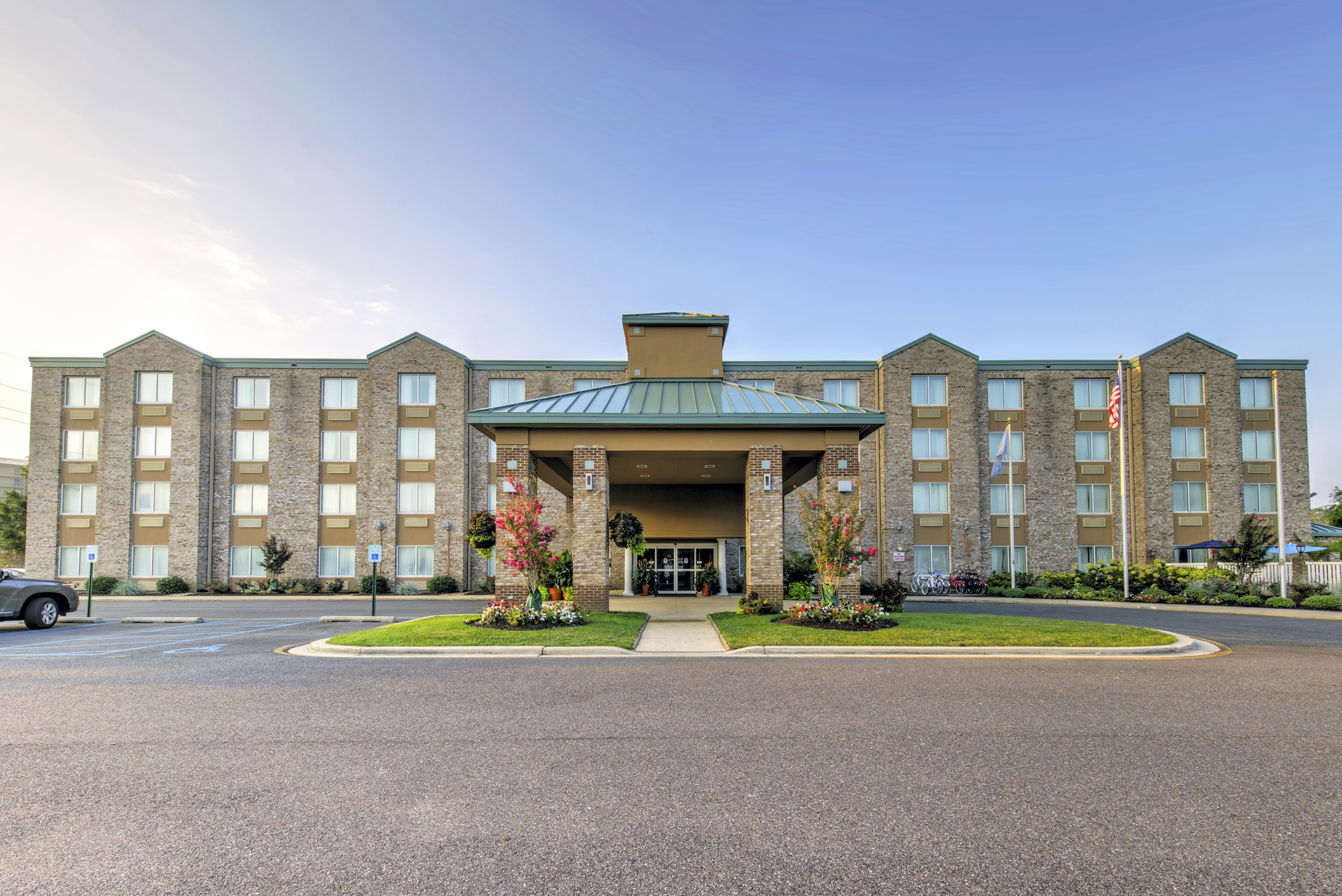 Hotel front view at sunrise with landscaped entrance.