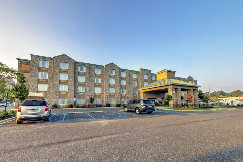 Hotel exterior and parking lot with morning sunlight.