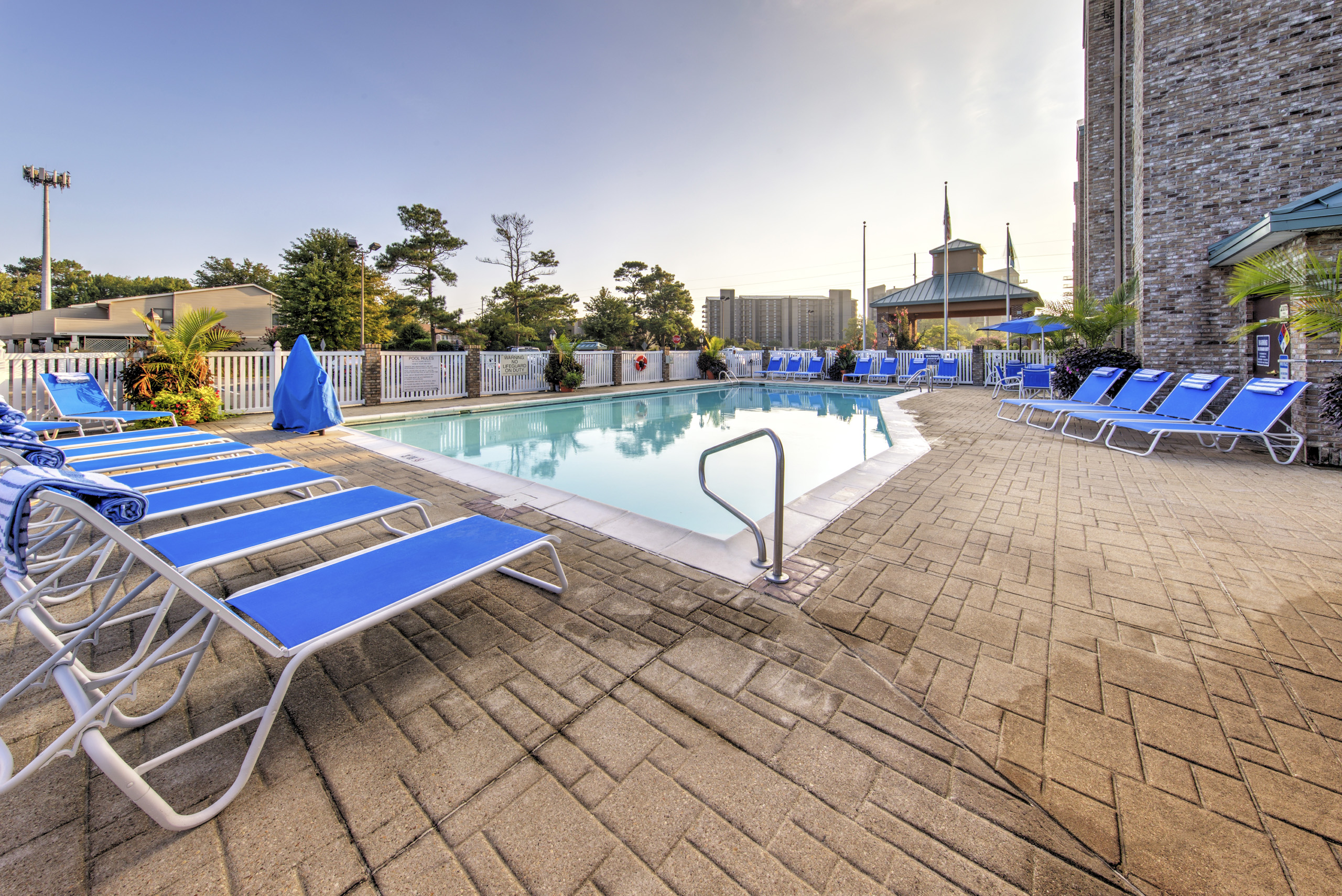Outdoor pool area with blue lounge chairs and umbrellas.