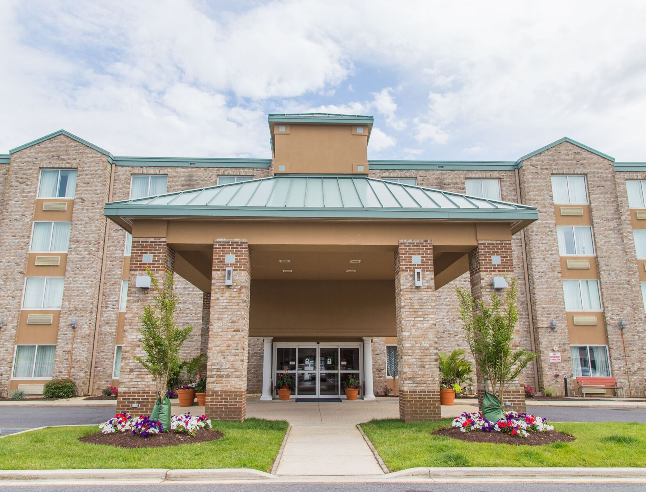 Hotel entrance with brick pillars and flowerbeds.