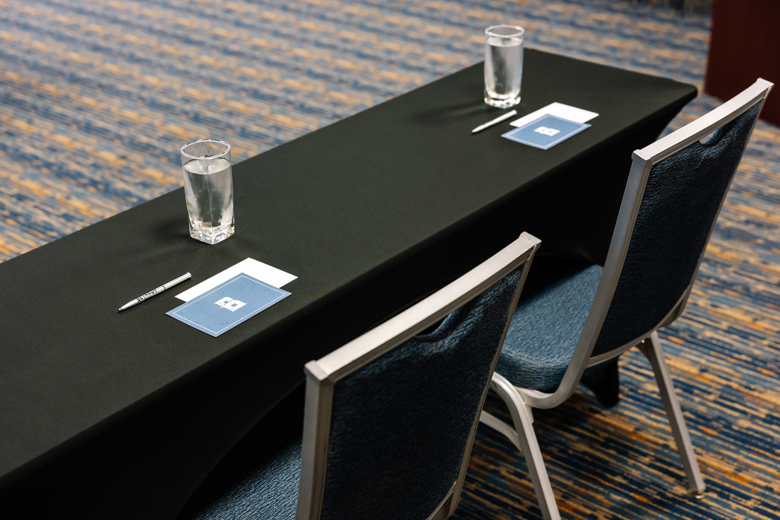 Meeting table setup with notepads, pens, and water glasses.