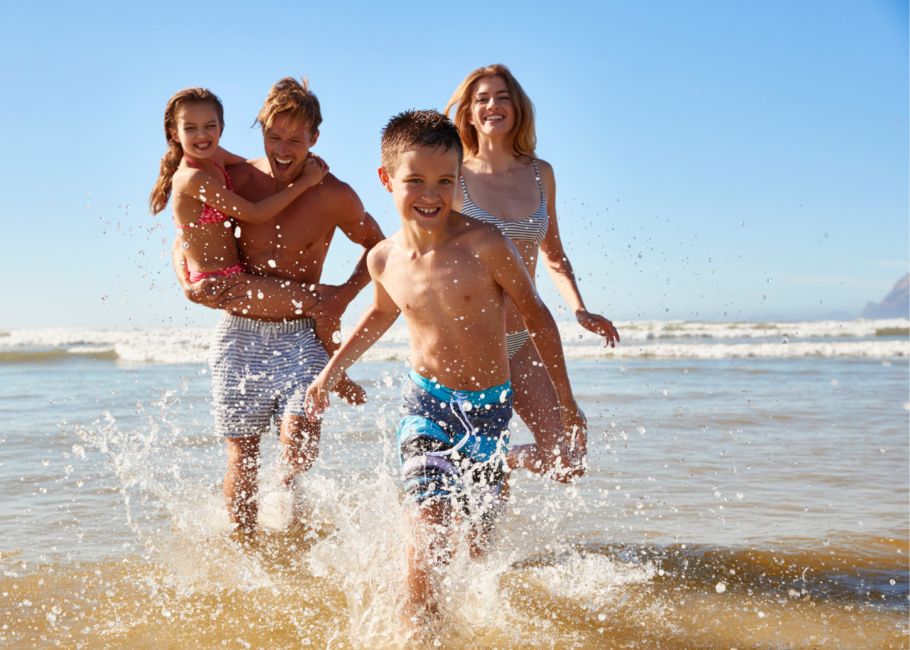 family running in ocean on beach