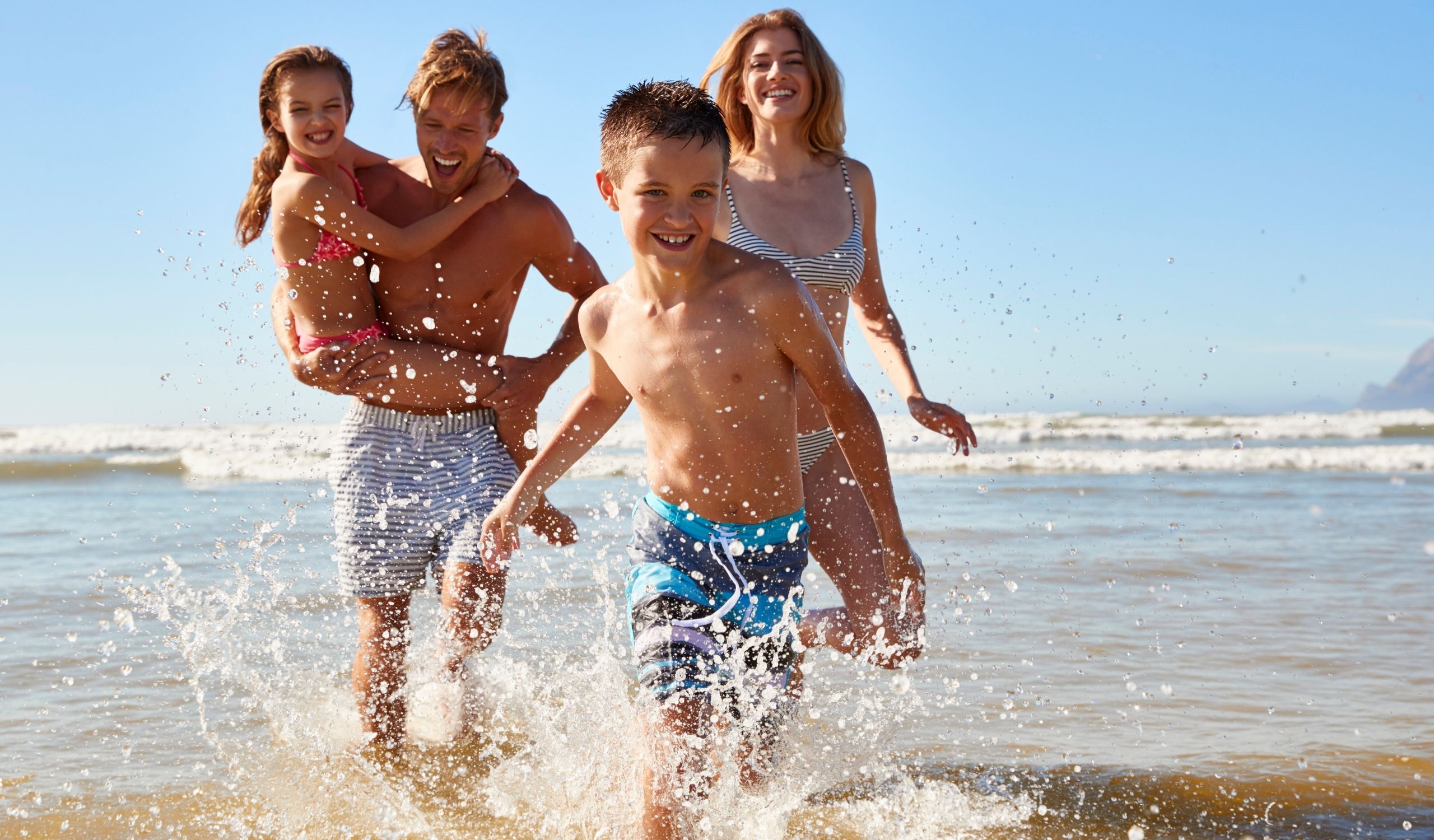 family running in ocean on beach